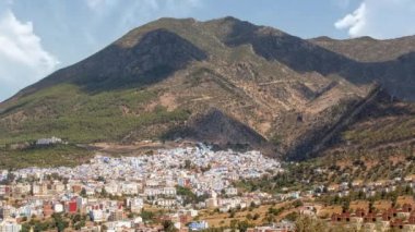 Güneşli bir günde şefin panoramik manzarasını hızlandırmak. Arkasında dağ olan mavi bir Afrika köyü var.