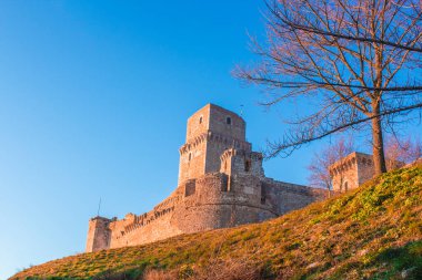 İtalya 'nın Umbria eyaletindeki Assisi tepesindeki ortaçağ şatosunun yakın görüntüsü. Taş tuğlalar gökyüzü bulutsuz, gökyüzü bulutsuz. 