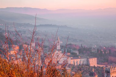 Umbria şehrinin gökdeleni ve günbatımında gökdelenin muhteşem manzarası. Tepeden güzel bir gece manzarası, arka planda Aziz Francis kilisesi ya da Bazilika ve tepesi var.