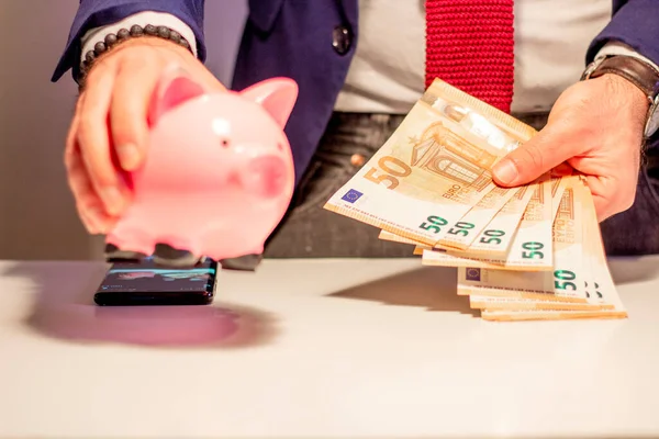 Business man showing in hand fifty euro banknote and holding piggy bank. Financial and money saving concept