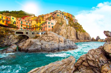 Liguria 'da Akdeniz kıyısındaki dağdaki Cinque Terre' de Manarola. Güneşli bulutlu gökyüzü. Geleneksel İtalyan mimarisi