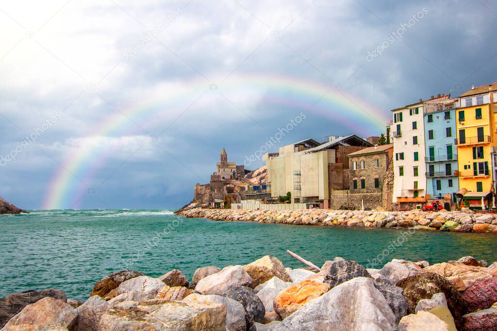 Rainbow on Portovenere (Porto Venere) in Liguria, Italy: scenic view of the Church of St. Peter (Chiesa di San Pietro) at sunset with colorful sunset nearby Cinque Terre