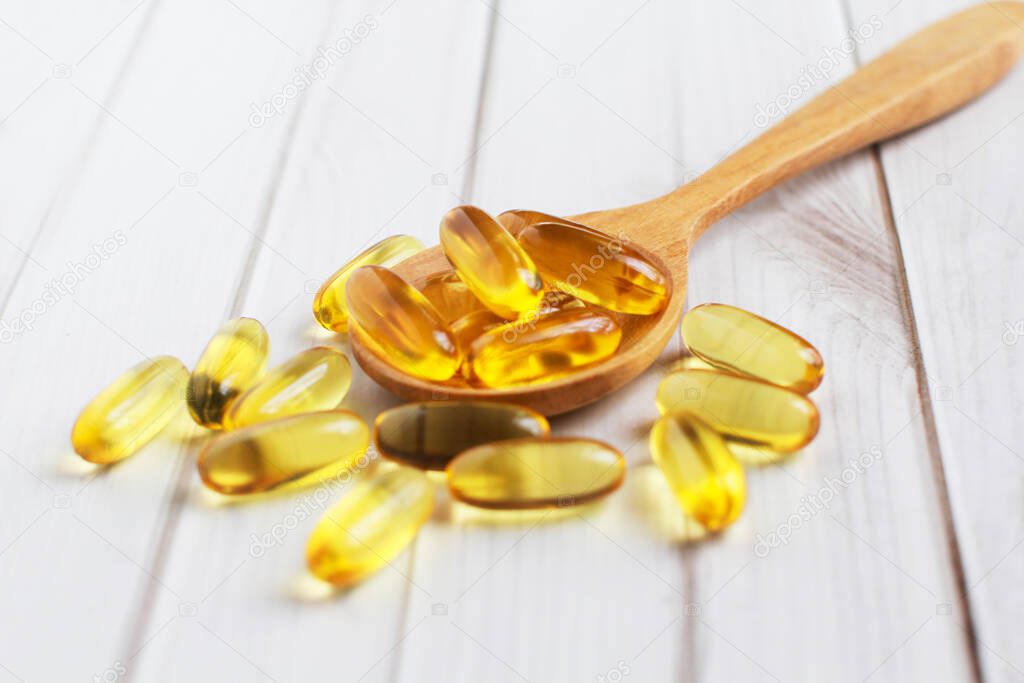 Fish oil capsules on wooden background and texture, Fish oil capsule placed on a wooden spoon, spot focus.