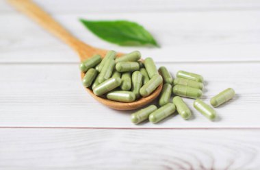 Andrographis tahta arka planda tahta kaşıkla panikleme kapsülü, bitkisel özüt ilaç hapları..