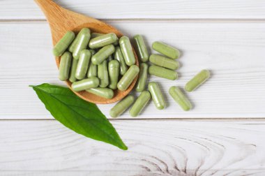 Andrographis tahta arka planda tahta kaşıkla panikleme kapsülü, bitkisel özüt ilaç hapları..