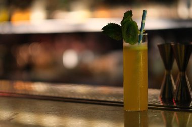 Bar tezgahındaki sarı renkli içeceği kapat. renkli bokeh