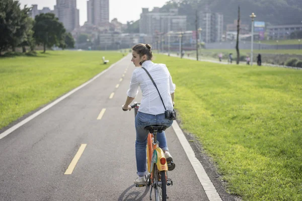 Kvinna med cykel i parken Royaltyfria Stockbilder