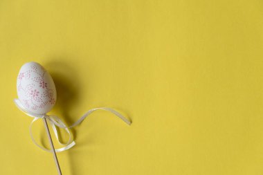 Tahta bir çubukta beyaz Paskalya yumurtası, güzel sarı bir arka plan.