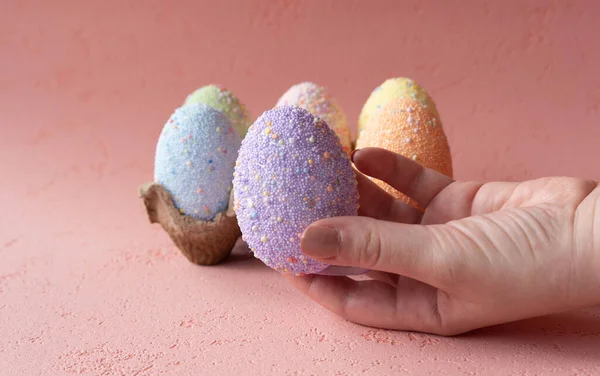 Easter egg in hand, box of eggs, beautiful pink background