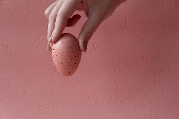 Easter egg in hand, pink egg, beautiful pink background