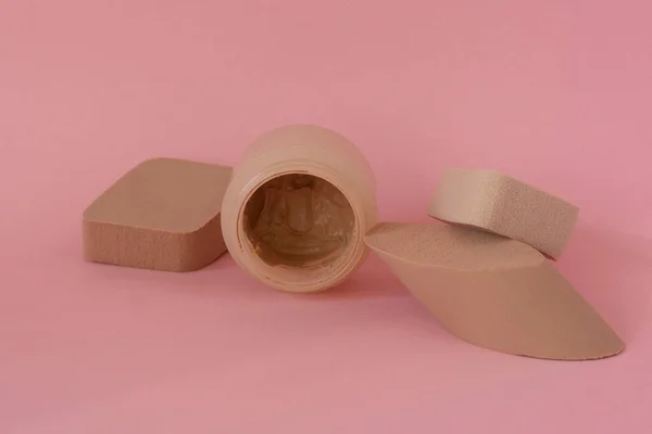 Pudra makyajı, pembe arka plana yüz pudrası sürmek için süngerler.