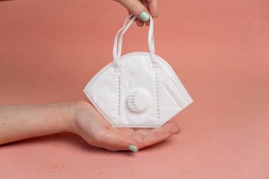 Kadınların elindeki virüs tacına karşı KN95 maskesi, pembe arka plan