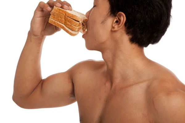 Musculoso asiático hombre carga carbohidratos comer algunos pan — Foto de Stock