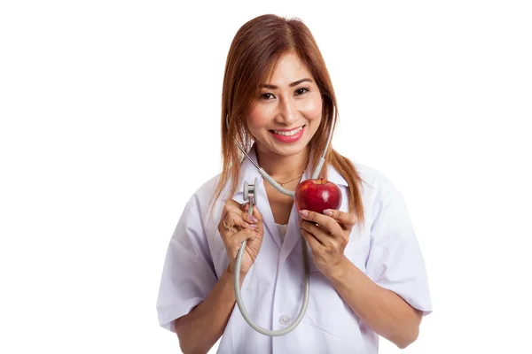 Unga asiatiska kvinnliga läkare lyssnar på ett äpple med en stethosco — Stockfoto