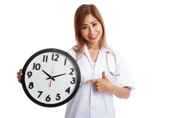 Joven asiática mujer médico punto a un reloj —  Fotos de Stock