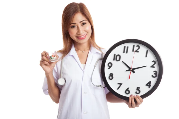 Junge asiatische Ärztin lächelt mit einer Uhr und Pillen in der Hand — Stockfoto