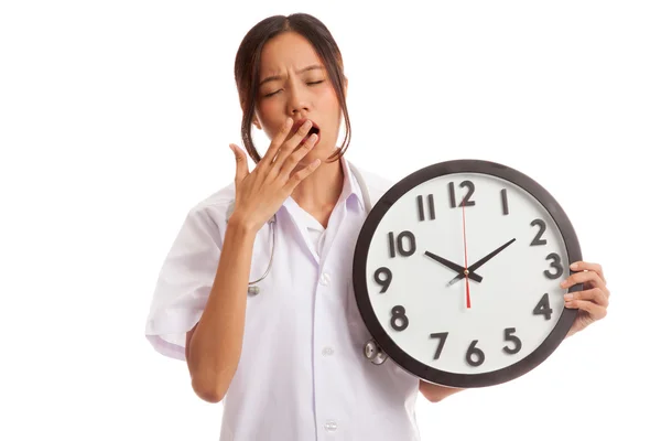 Young Asian female doctor yawn with a clock — Stock Photo, Image