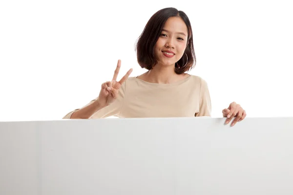 Mujer asiática joven muestra signo de victoria con signo en blanco — Foto de Stock