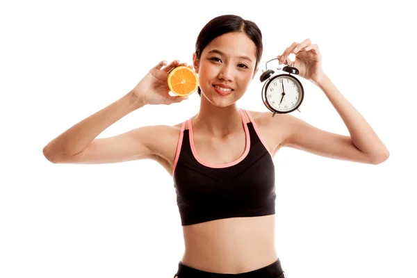 Азиатская здоровая девочка с апельсином и часами — стоковое фото