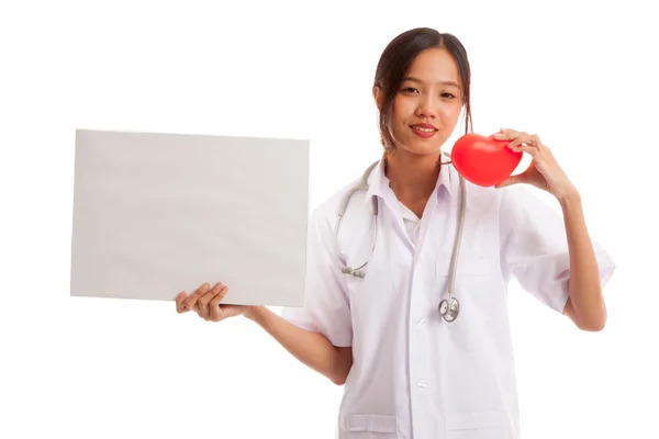 Junge asiatische Ärztin mit rotem Herz und leerem Schild — Stockfoto