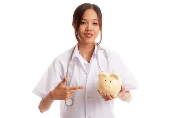 Joven mujer asiática médico punto a una moneda de banco de cerdo — Foto de Stock