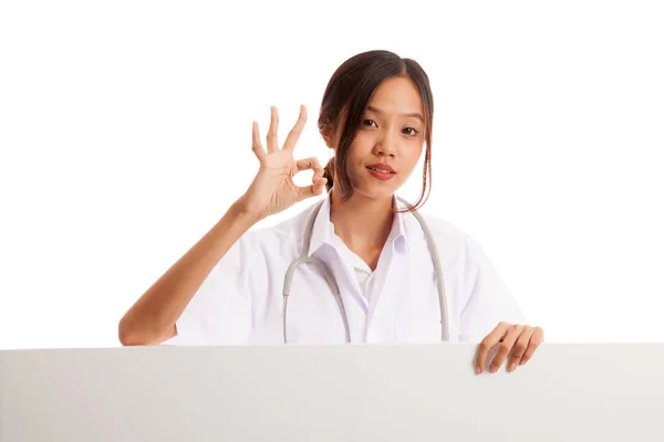 Junge asiatische weibliche Arzt zeigen ok Zeichen hinter leeren weißen Billb — Stockfoto