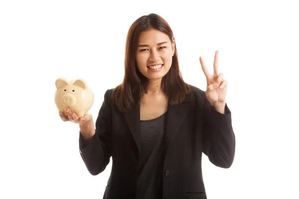 Mujer de negocios asiática muestra signo de victoria con banco de moneda de cerdo . — Foto de Stock