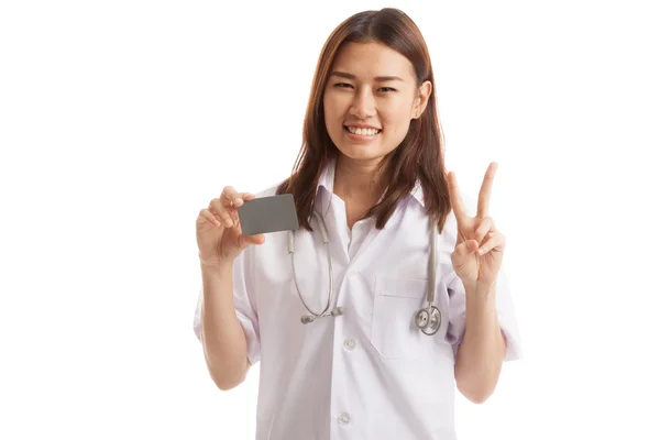 Asiatische junge Ärztin zeigt Siegeszeichen mit Blankokarte. — Stockfoto