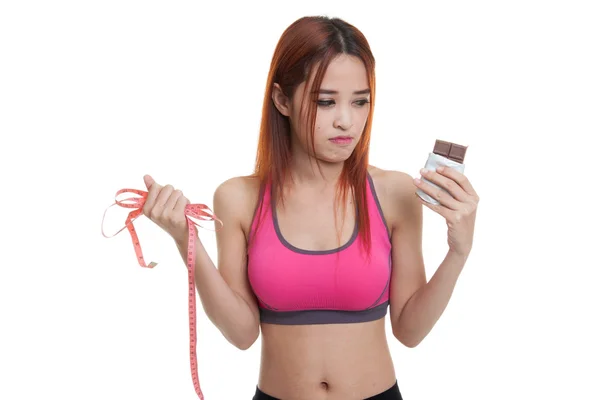 Несчастная азиатская здоровая девушка с шоколадом и измерительной лентой . — стоковое фото