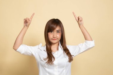 Genç Asyalı kadın bej arka planda boş bir alanı işaret ediyor