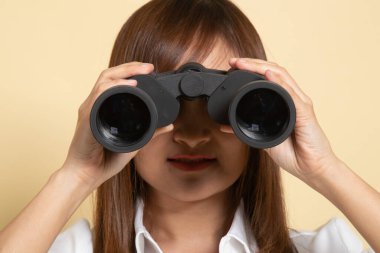 Bej arka planda dürbünü olan genç Asyalı kadın.