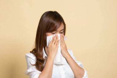 Genç Asyalı kadın hastalandı ve bej arka planda grip oldu.