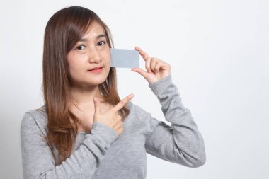 Genç Asyalı kadın beyaz arka planda boş bir karta işaret ediyor.