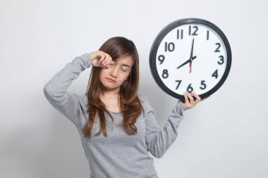 Beyaz arka plan üzerinde sabah bir saat ile uykulu genç Asyalı kadın