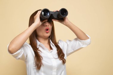 Bej arka planda dürbünü olan genç Asyalı kadın.