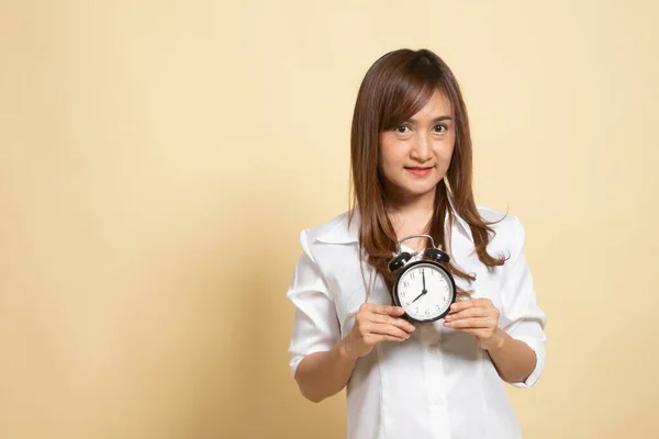 年轻的亚洲女人笑着带着米色背景的时钟 — 图库照片