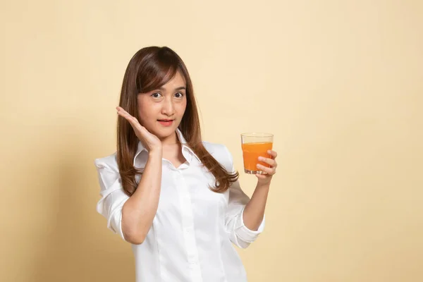 快乐的年轻亚洲女人在米色背景下喝橙汁 — 图库照片