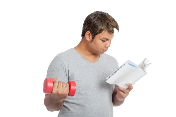 Asian man reading a book with red dumbbell — Stock Photo, Image