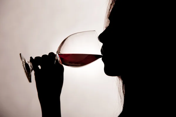 Silhouette shot di una donna che beve vino rosso . — Foto Stock