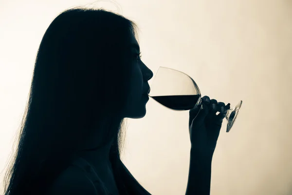 Silhouette shot di una donna che beve vino rosso . — Foto Stock