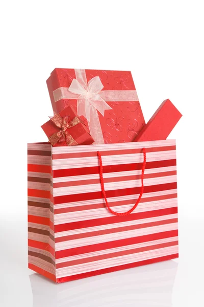 Red gift boxes in red shopping bag — Stock Photo, Image