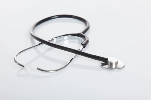 Black Stethoscope on white glossy table — Stock Photo, Image