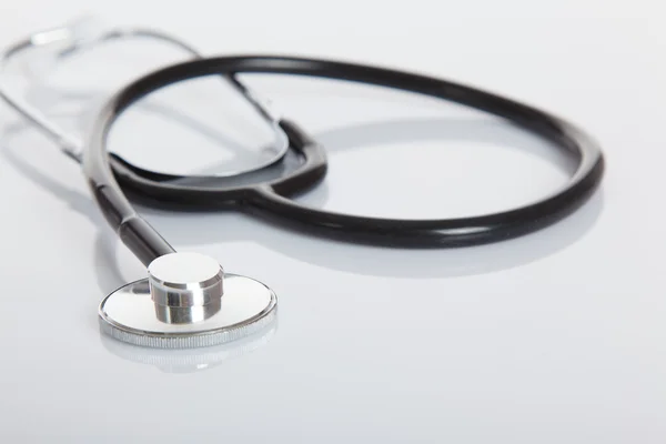 Black Stethoscope on white glossy table — Stock Photo, Image