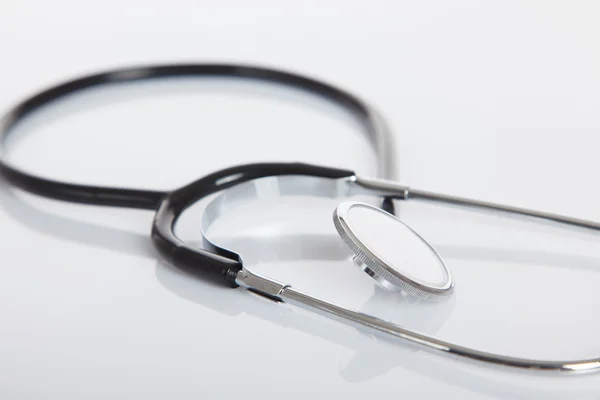 Black Stethoscope on white glossy table — Stock Photo, Image