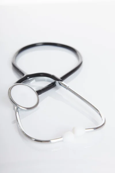 Black Stethoscope on white glossy table — Stock Photo, Image