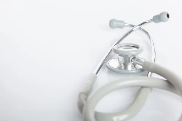 Gray stethoscope on white glossy table — Stock Photo, Image