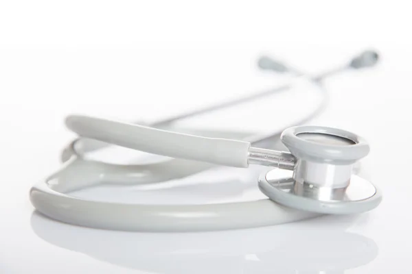 Gray stethoscope on white glossy table — Stock Photo, Image