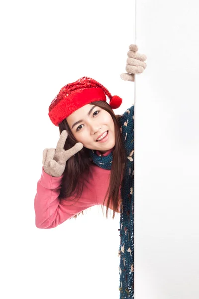 Asian girl with red christmas hat peeking from behind blank bann — Stock Photo, Image