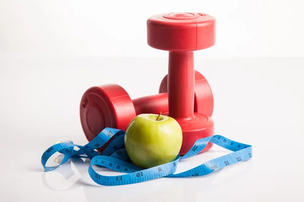 Peso de halteres vermelhos com fita métrica e maçã verde — Fotografia de Stock