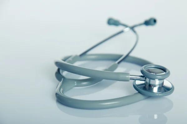 Gray stethoscope on white glossy table — Stock Photo, Image